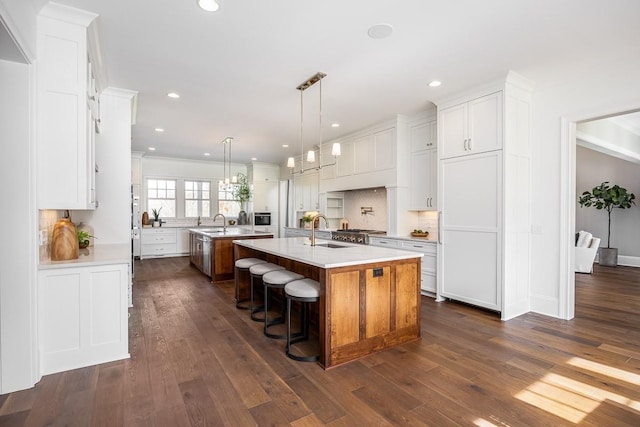 kitchen featuring white cabinetry, sink, dark hardwood / wood-style floors, a kitchen island with sink, and a breakfast bar