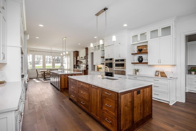 kitchen featuring a center island with sink, decorative light fixtures, white cabinets, and sink