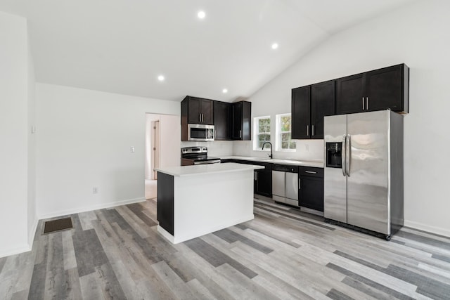 kitchen featuring light wood-type flooring, stainless steel appliances, a kitchen island, and high vaulted ceiling