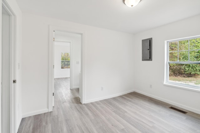 empty room with electric panel and light hardwood / wood-style flooring