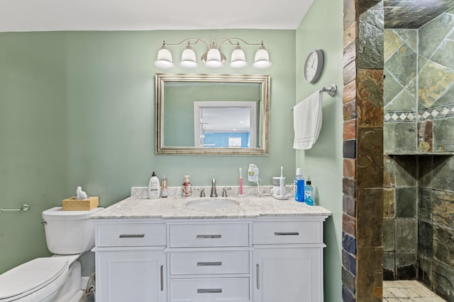 bathroom featuring vanity, tiled shower, and toilet