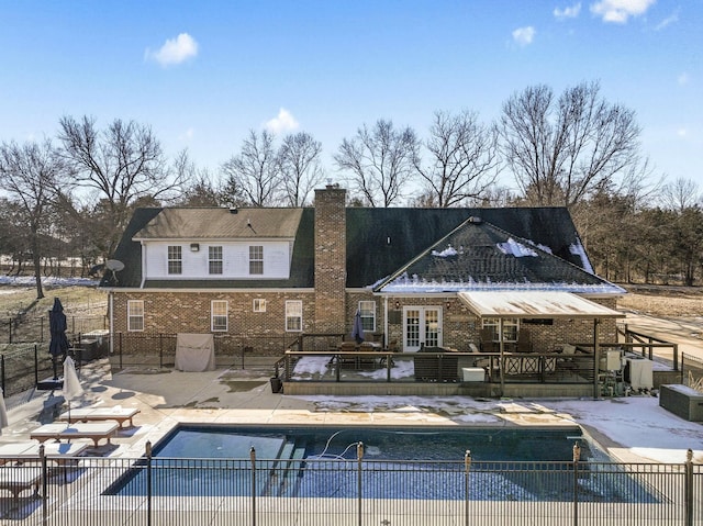 rear view of house featuring a covered pool and a patio