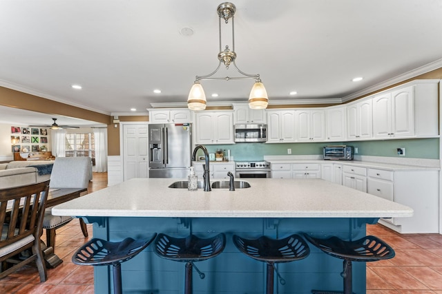 kitchen with stainless steel appliances, a center island with sink, ceiling fan, and white cabinets