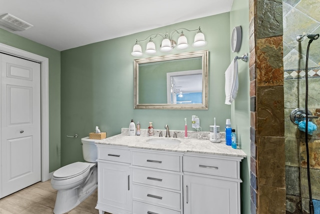 bathroom featuring toilet, wood-type flooring, vanity, and walk in shower