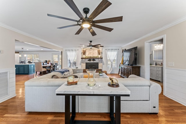 living room featuring hardwood / wood-style flooring, ceiling fan, crown molding, and a wealth of natural light