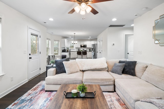 living room with hardwood / wood-style floors and ceiling fan with notable chandelier