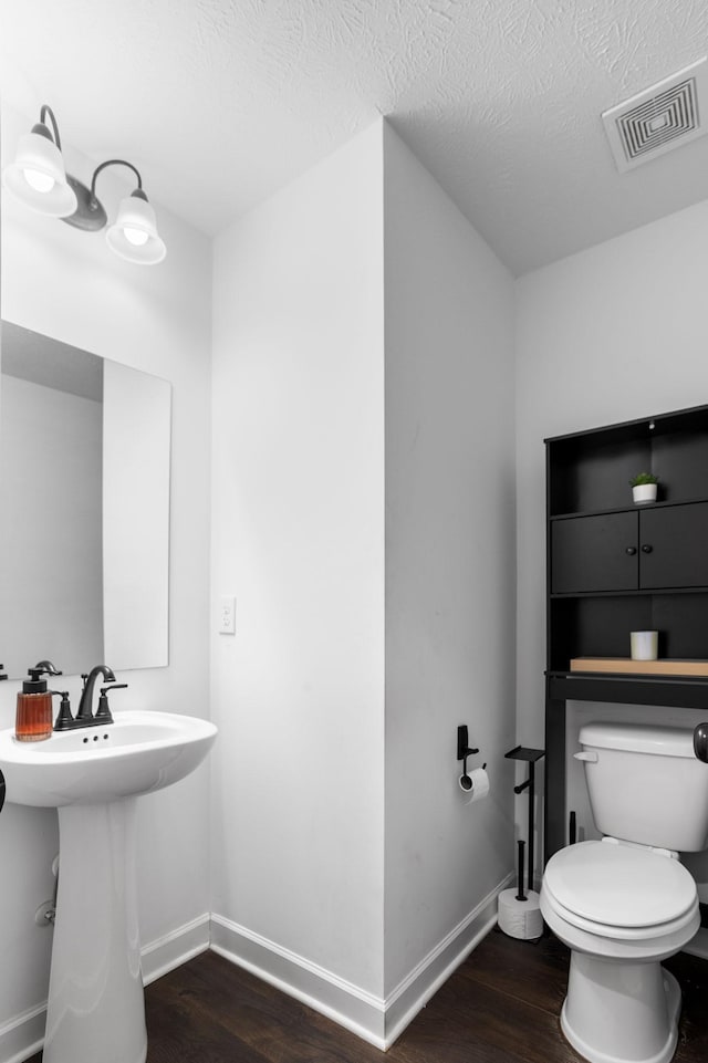 bathroom with toilet, a textured ceiling, and hardwood / wood-style flooring