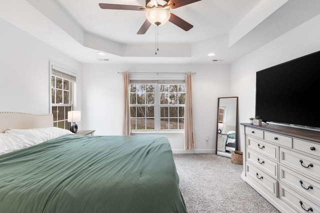 bedroom with ceiling fan, a raised ceiling, and light colored carpet