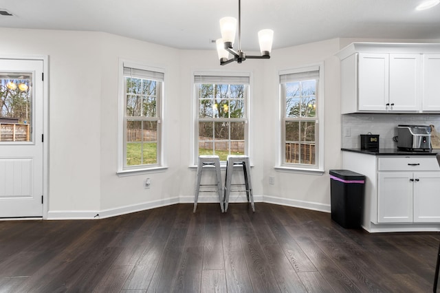 unfurnished dining area featuring dark wood-type flooring and an inviting chandelier