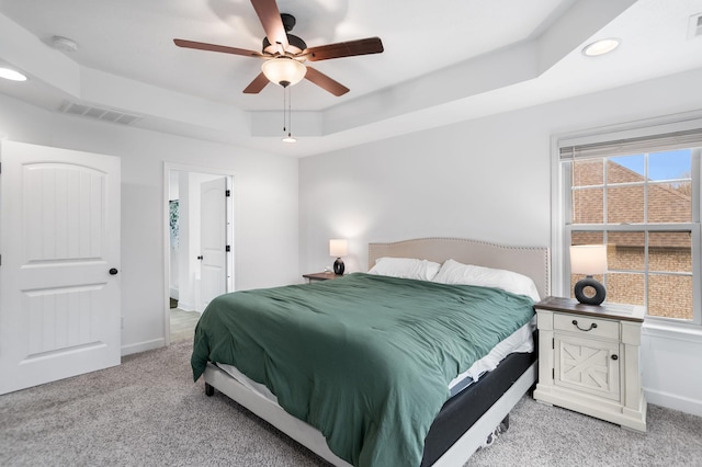 bedroom featuring a tray ceiling, ceiling fan, and light carpet