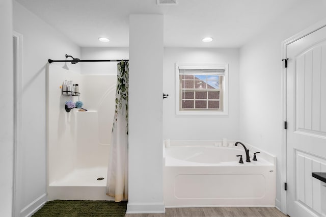 bathroom with independent shower and bath and wood-type flooring