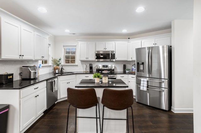 kitchen featuring dark wood-type flooring, a center island, white cabinets, and stainless steel appliances