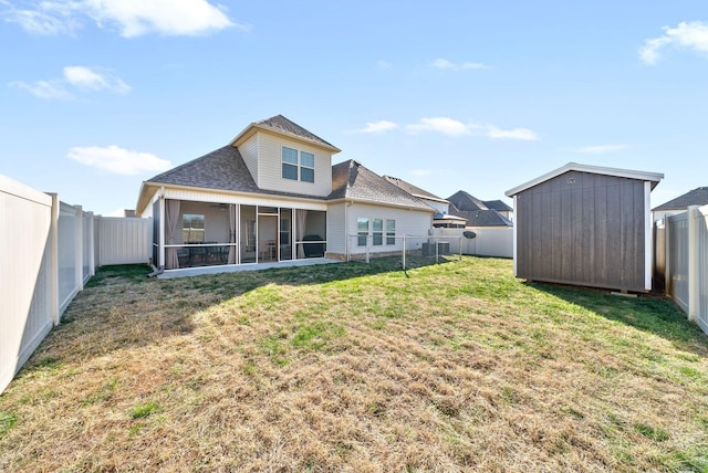 rear view of property featuring a yard, a sunroom, and a storage shed