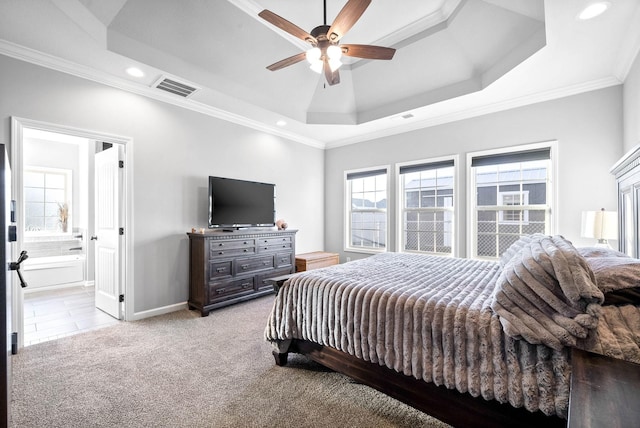 bedroom with a raised ceiling, connected bathroom, ceiling fan, ornamental molding, and light colored carpet