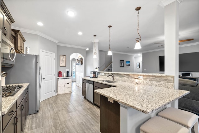 kitchen featuring appliances with stainless steel finishes, a breakfast bar, pendant lighting, sink, and dark brown cabinets