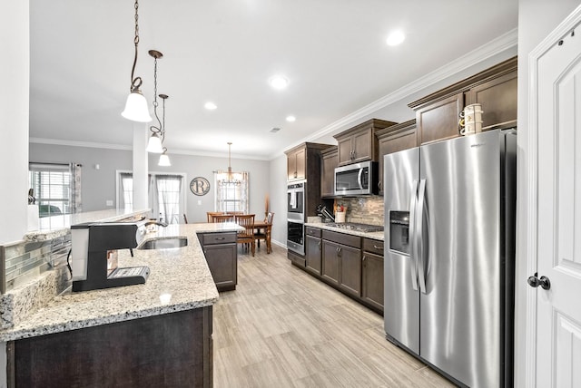 kitchen with stainless steel appliances, hanging light fixtures, decorative backsplash, sink, and dark brown cabinets