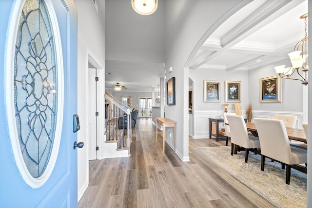 foyer entrance with beamed ceiling, ornamental molding, hardwood / wood-style flooring, ceiling fan with notable chandelier, and coffered ceiling