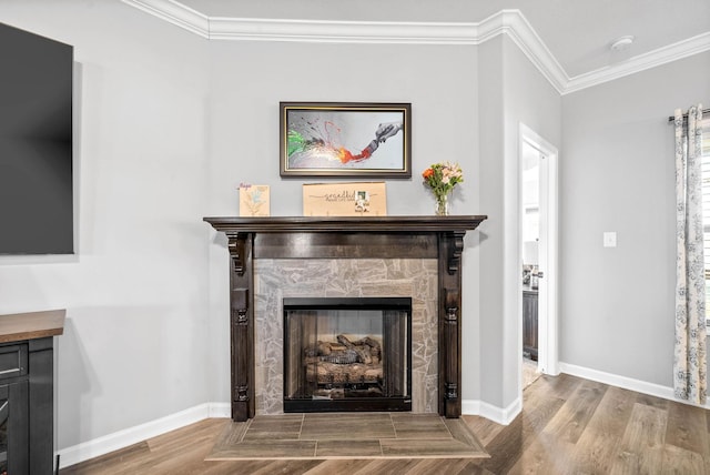 interior details featuring hardwood / wood-style floors, ornamental molding, and a stone fireplace