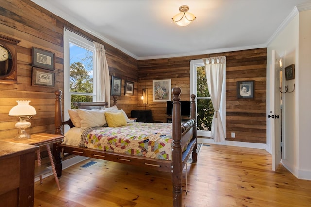 bedroom with crown molding, wood walls, and hardwood / wood-style flooring