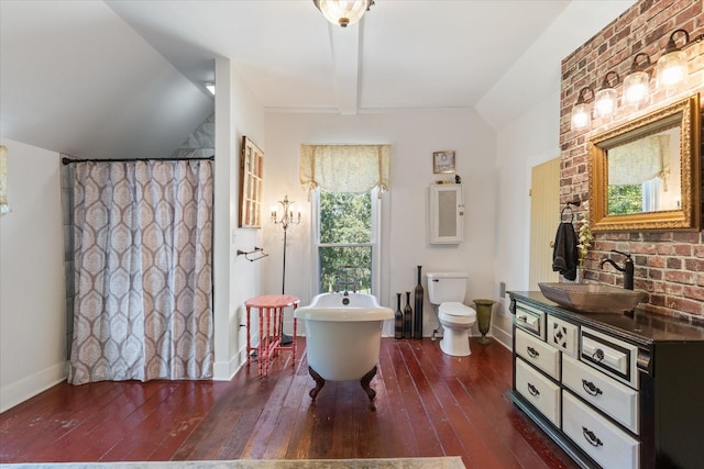 bathroom featuring vanity, a bath, hardwood / wood-style floors, toilet, and lofted ceiling