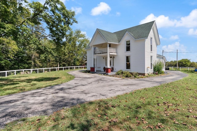 view of front of property featuring a balcony and a front yard