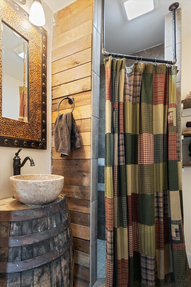 bathroom with a shower with curtain, wooden walls, and sink