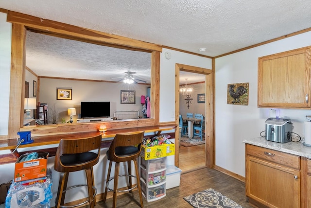 kitchen with ceiling fan with notable chandelier, dark wood-type flooring, a textured ceiling, and ornamental molding