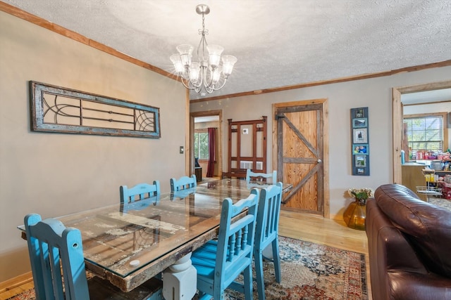 dining area with ornamental molding, a textured ceiling, and an inviting chandelier