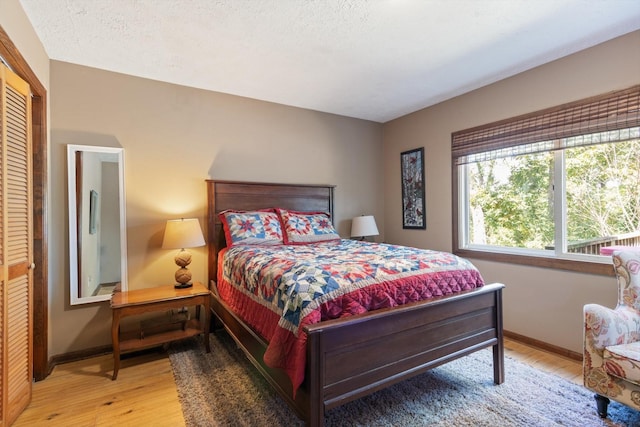 bedroom with light wood-type flooring, a textured ceiling, and a closet