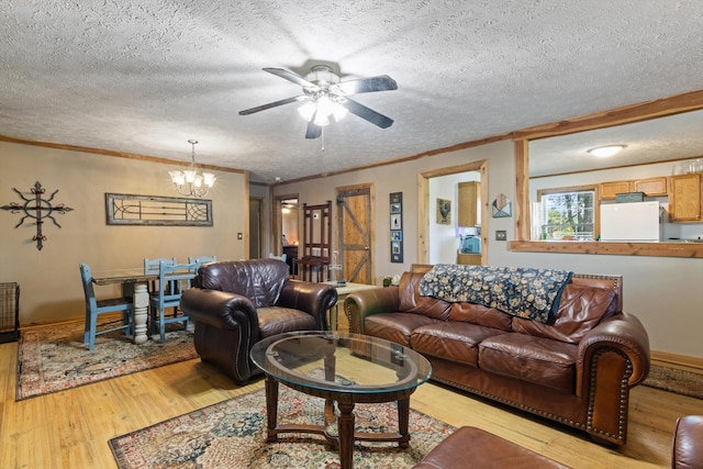 living room with ceiling fan with notable chandelier, crown molding, light wood-type flooring, and a textured ceiling