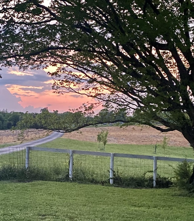 yard at dusk featuring a rural view