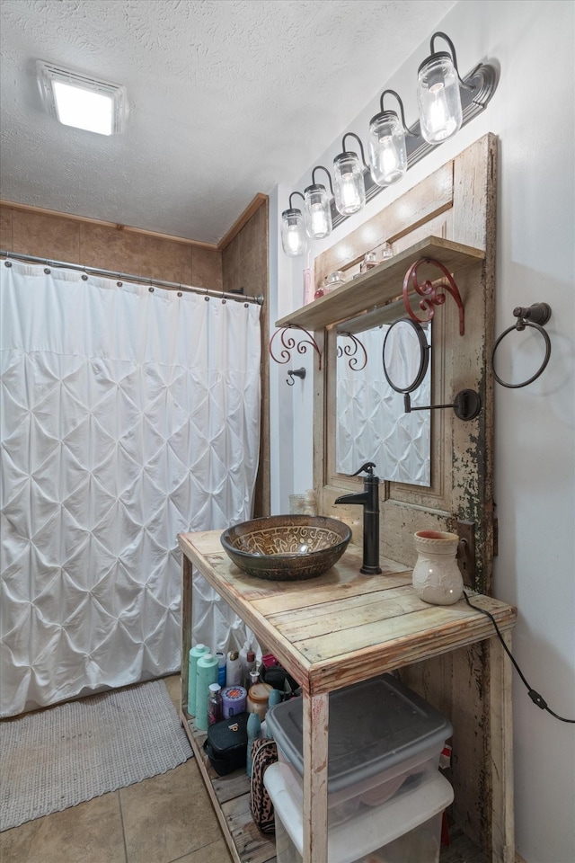 bathroom with a textured ceiling and tile patterned floors