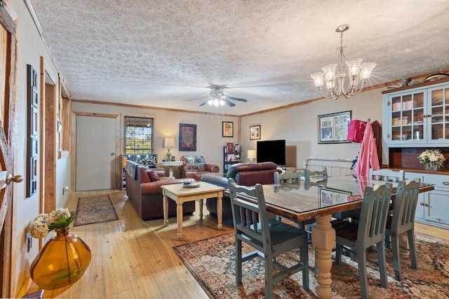 dining area featuring a textured ceiling, ceiling fan with notable chandelier, light hardwood / wood-style floors, and crown molding