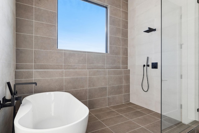 bathroom with tile patterned flooring, plus walk in shower, and tile walls