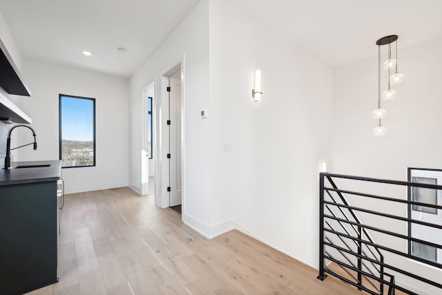 hallway with light wood-type flooring and sink