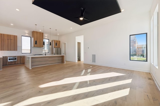 kitchen with hanging light fixtures, a center island, light hardwood / wood-style flooring, and ceiling fan