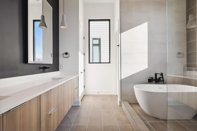 bathroom with a tub to relax in, a wealth of natural light, tile patterned flooring, and vanity