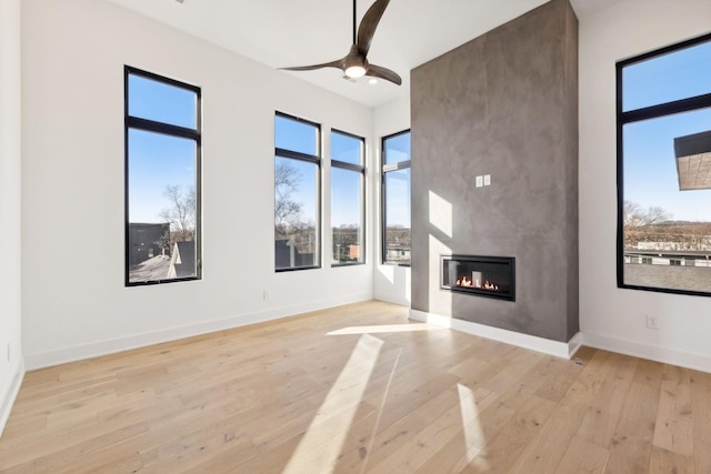 unfurnished living room featuring ceiling fan, light wood-type flooring, and a fireplace