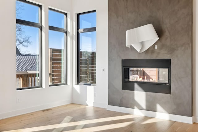 empty room with a multi sided fireplace and light wood-type flooring