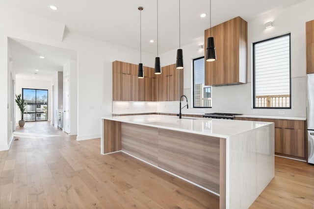 kitchen with a center island with sink, sink, and hanging light fixtures