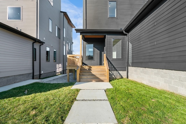 view of exterior entry with a deck and a lawn