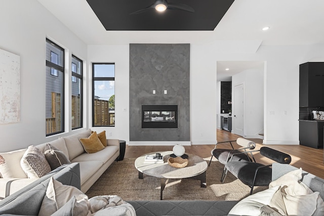 living room with hardwood / wood-style flooring, ceiling fan, and a multi sided fireplace