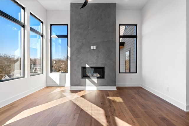 unfurnished living room featuring a fireplace, hardwood / wood-style floors, and ceiling fan