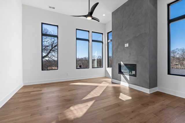 unfurnished living room featuring ceiling fan, a large fireplace, and light hardwood / wood-style flooring