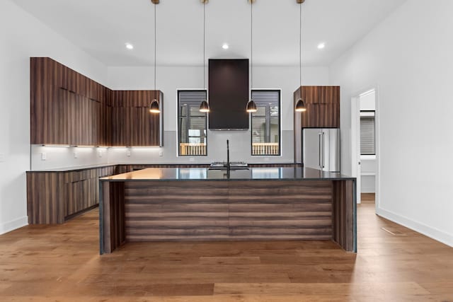 kitchen with a center island, light hardwood / wood-style flooring, high quality fridge, and exhaust hood