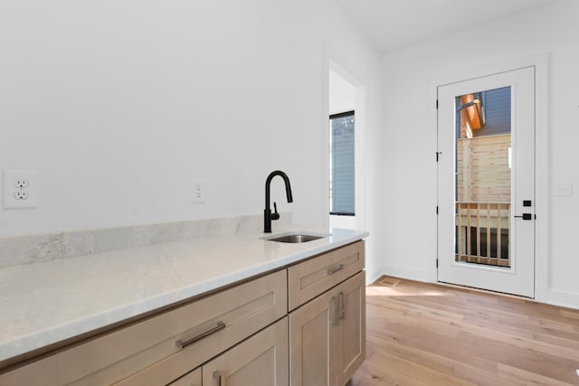 kitchen with light brown cabinets, light wood-type flooring, and sink