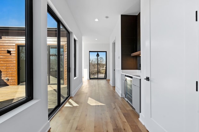 hall featuring a wealth of natural light, beverage cooler, and light wood-type flooring