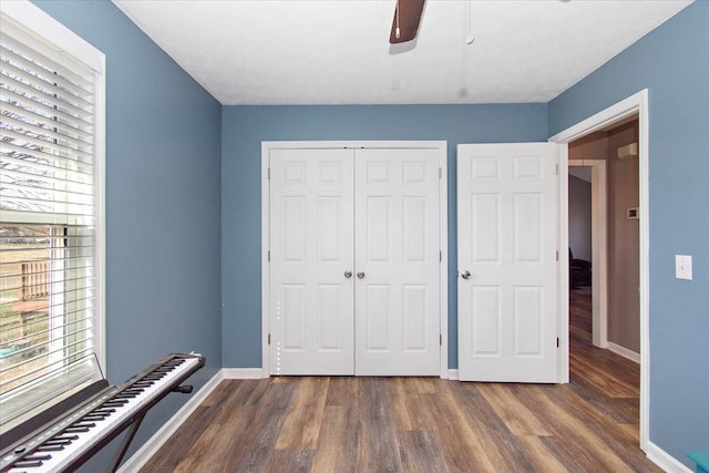 unfurnished bedroom featuring ceiling fan, dark hardwood / wood-style floors, and a closet