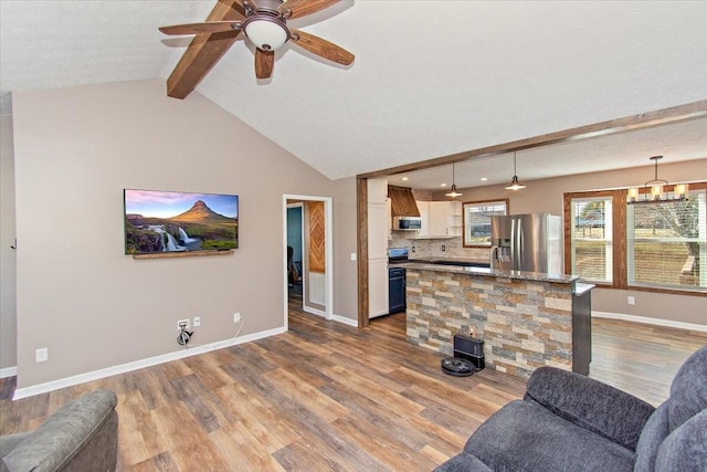 living room featuring ceiling fan with notable chandelier, lofted ceiling with beams, and light hardwood / wood-style floors