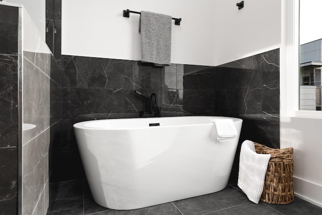 bathroom with a tub to relax in, tile walls, and tile patterned flooring